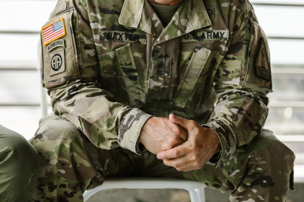 Gros plan sur un soldat en uniforme camouflage, patchs et insignes de grade visibles