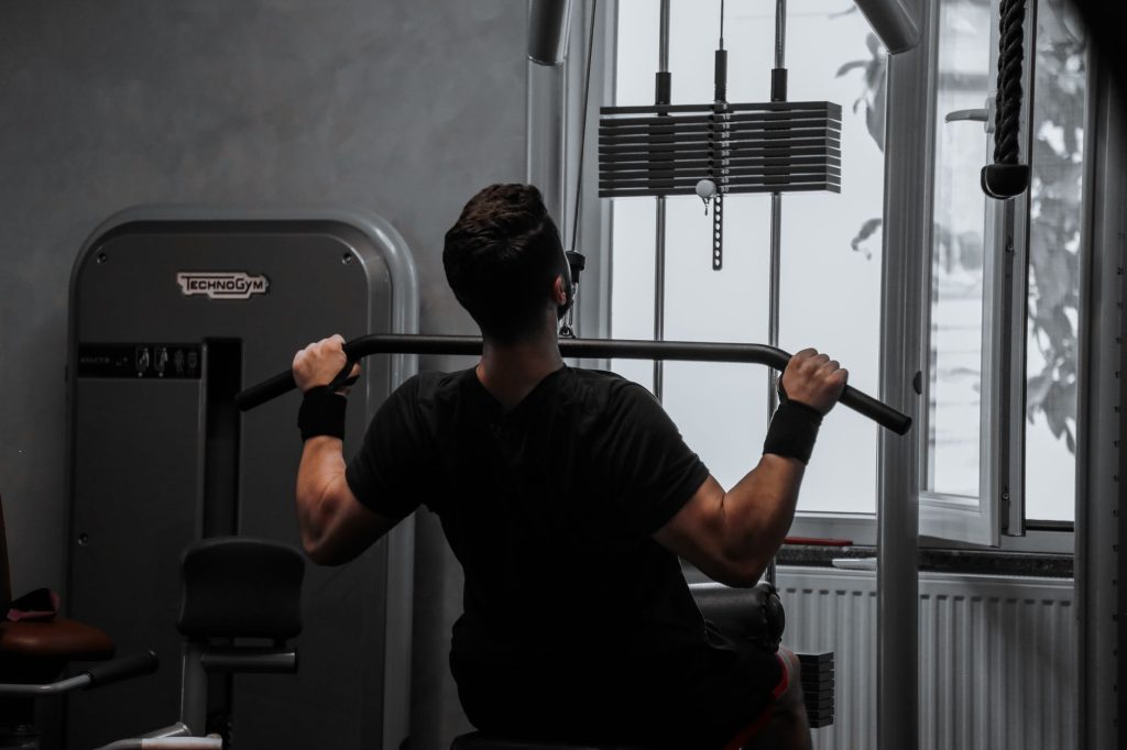 Homme s'entraînant sur une machine de tirage vertical dans une salle de sport, focus sur le dos