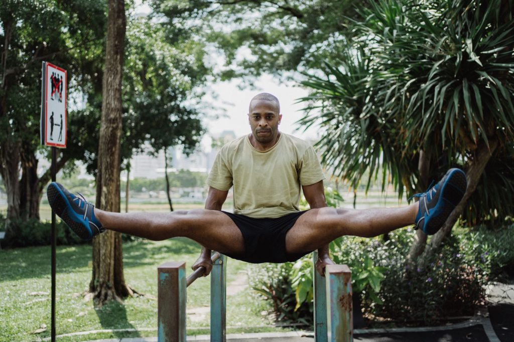 Homme afro-américain exécutant un exercice sur des barres parallèles extérieures, force et souplesse.
