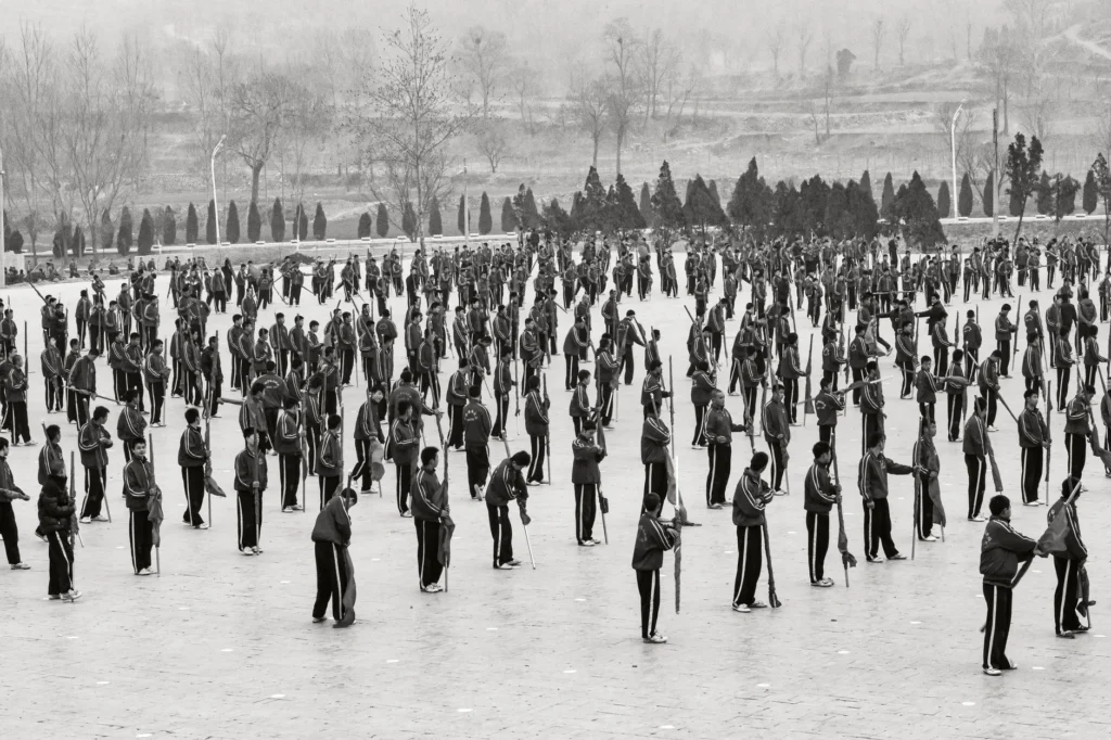 Photo en noir et blanc d'un grand groupe en uniforme formant des rangs en extérieur
